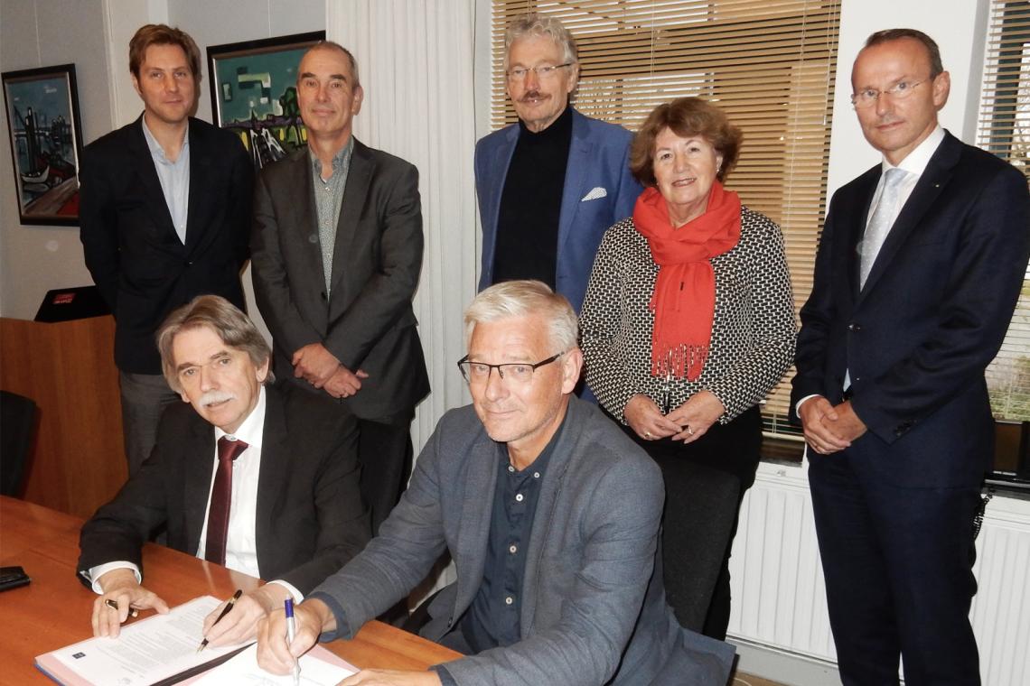 Burgemeester Gerard Beukema (links) en Jan Koolhof, voorzitter Stichting DelfSail 2021 tekenen de uitvoeringsovereenkomst. Staand v.l.n.r.: Arjen Luinenburg, gemeente Delfzijl, de wethouders Hans Ronde en Jan Menninga, Jeannette Blijdorp (directeur DelfSail 2021) en Johan Smit (penningmeester DelfSail 2021).